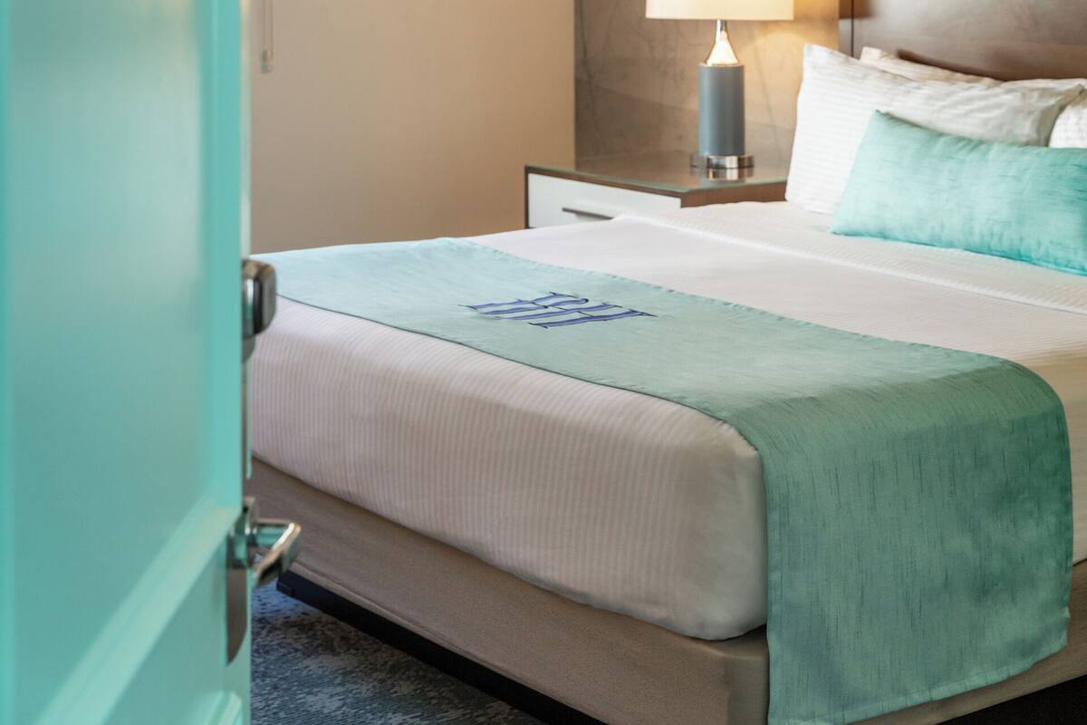 Ein Hotelzimmer mit einem Bett, einem Nachttisch mit Lampe und einer Wand mit floralem Wandbild.