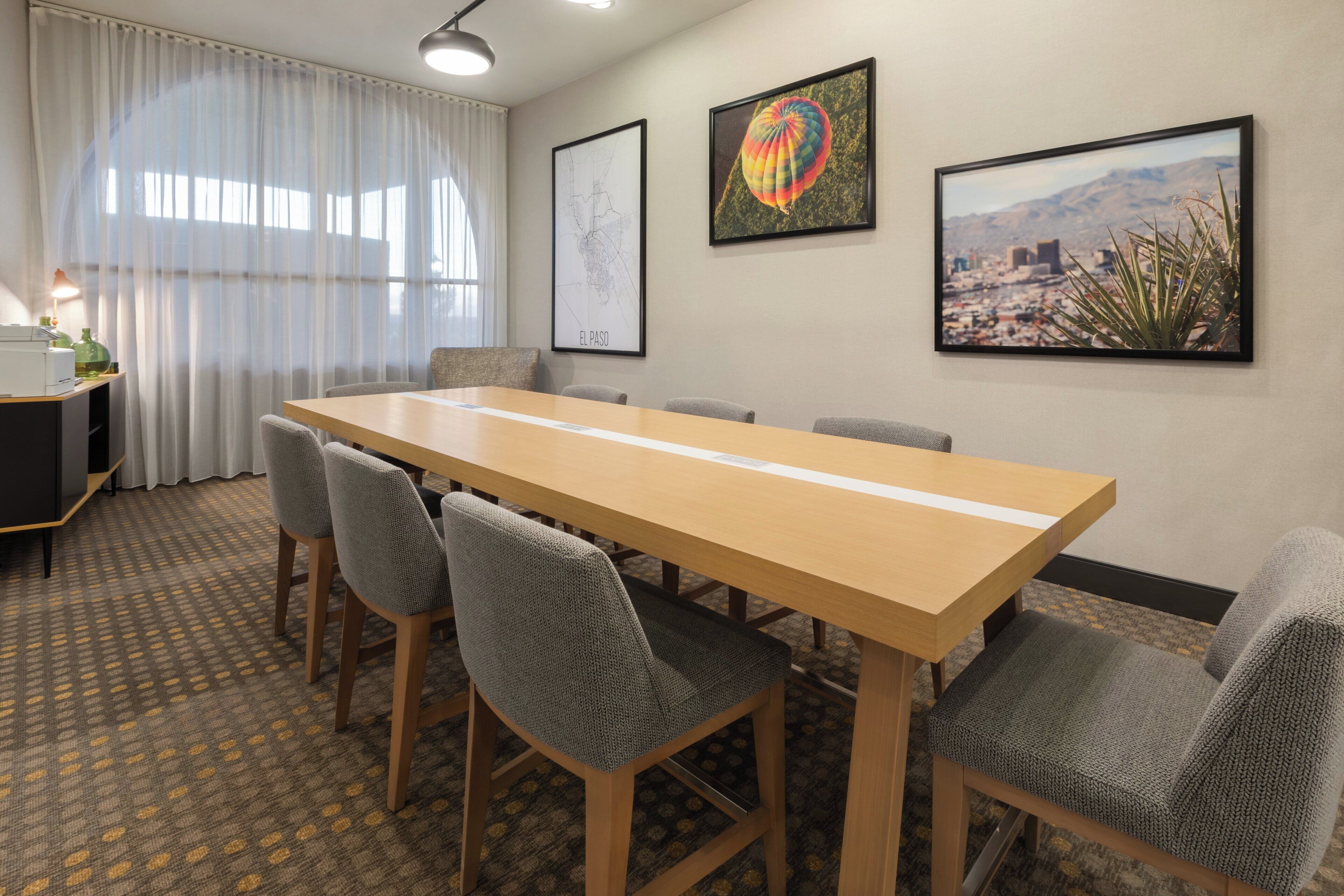 A conference room with a long table, six chairs, a map, and a hot air balloon picture on the wall.