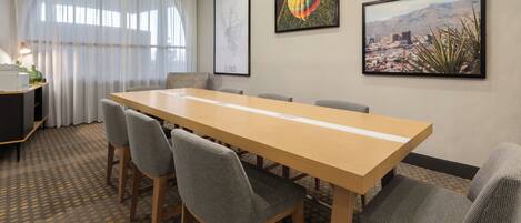 A conference room with a long table, six chairs, a map, and a hot air balloon picture on the wall.