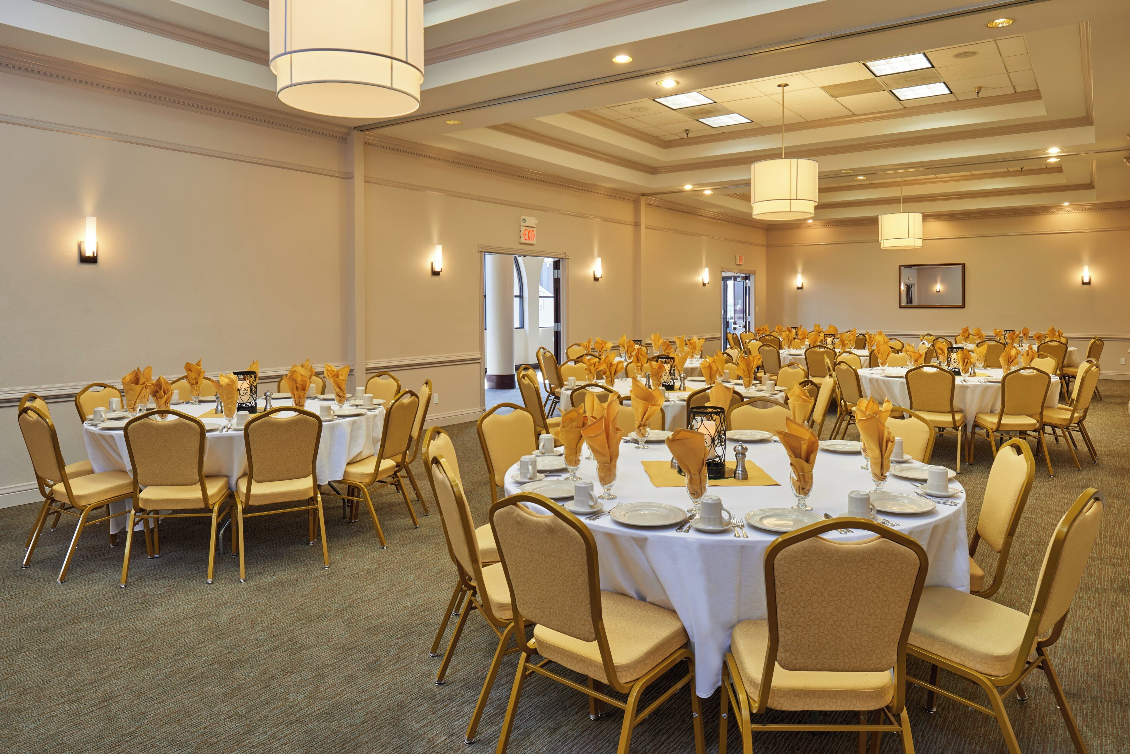 Un salón de banquetes con mesas redondas, sillas y mesas dispuestas para un evento formal.