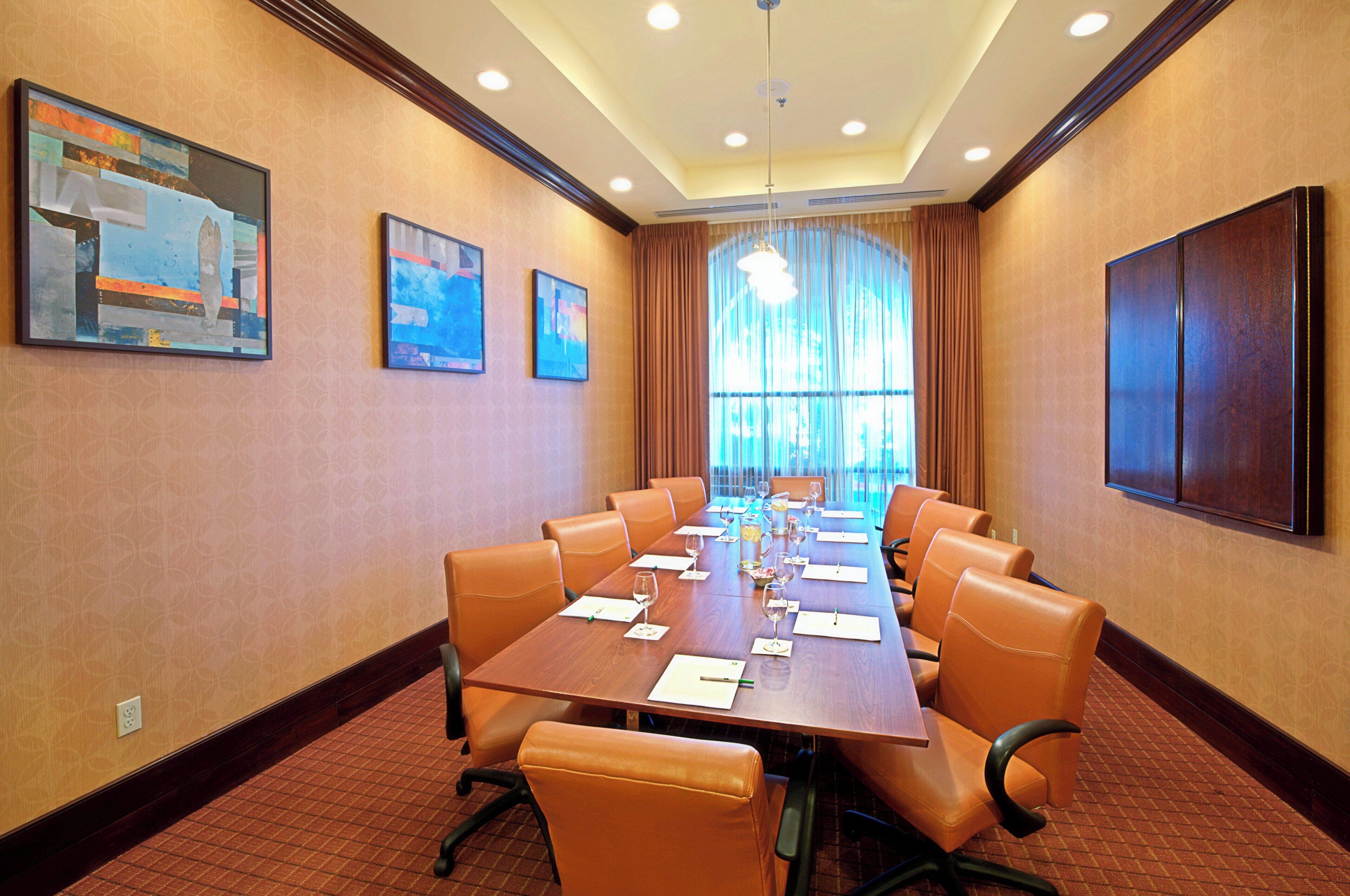 A conference room with a long table, multiple chairs, and artwork on the walls.