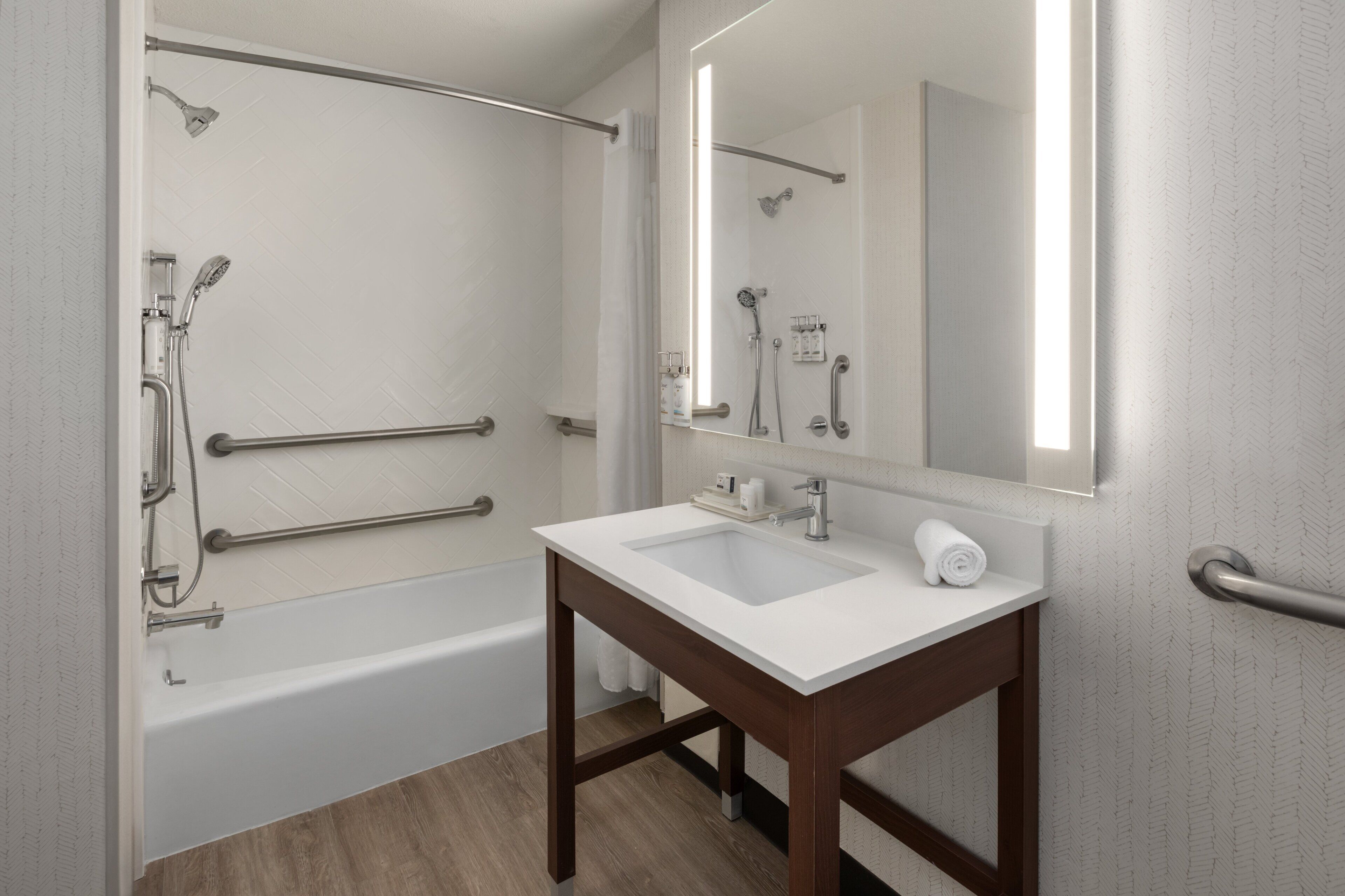 A bathroom with a white sink, mirror, and shower.
