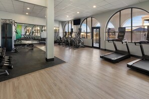 Un gimnasio con cintas de correr, elípticas y pesas sueltas.