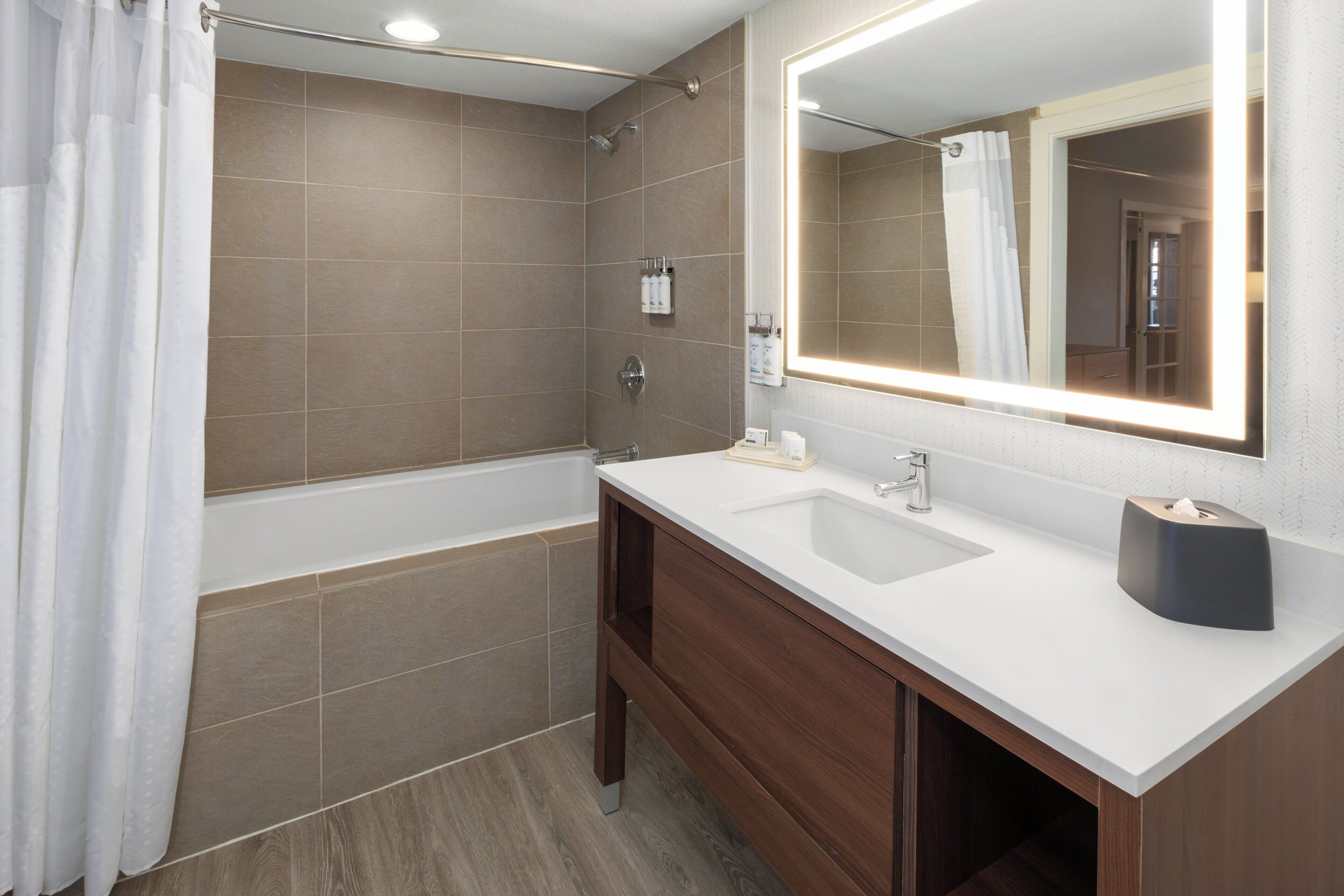 A modern bathroom with a bathtub, a sink, and a mirror.