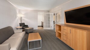 Une chambre d’hôtel moderne équipée d’un canapé, d’une petite table, d’un téléviseur et d’un meuble de rangement.