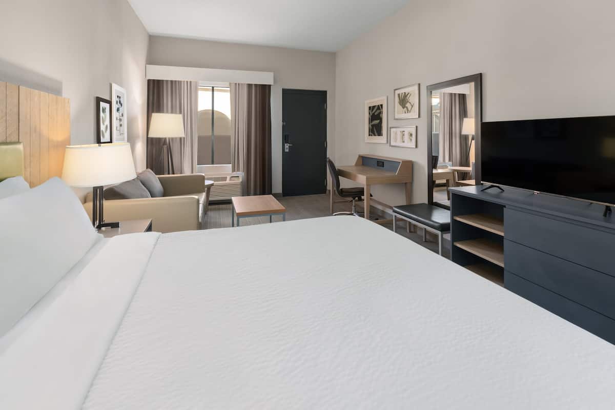 Une chambre d’hôtel avec un grand lit, un bureau, une chaise, une télévision et une armoire.