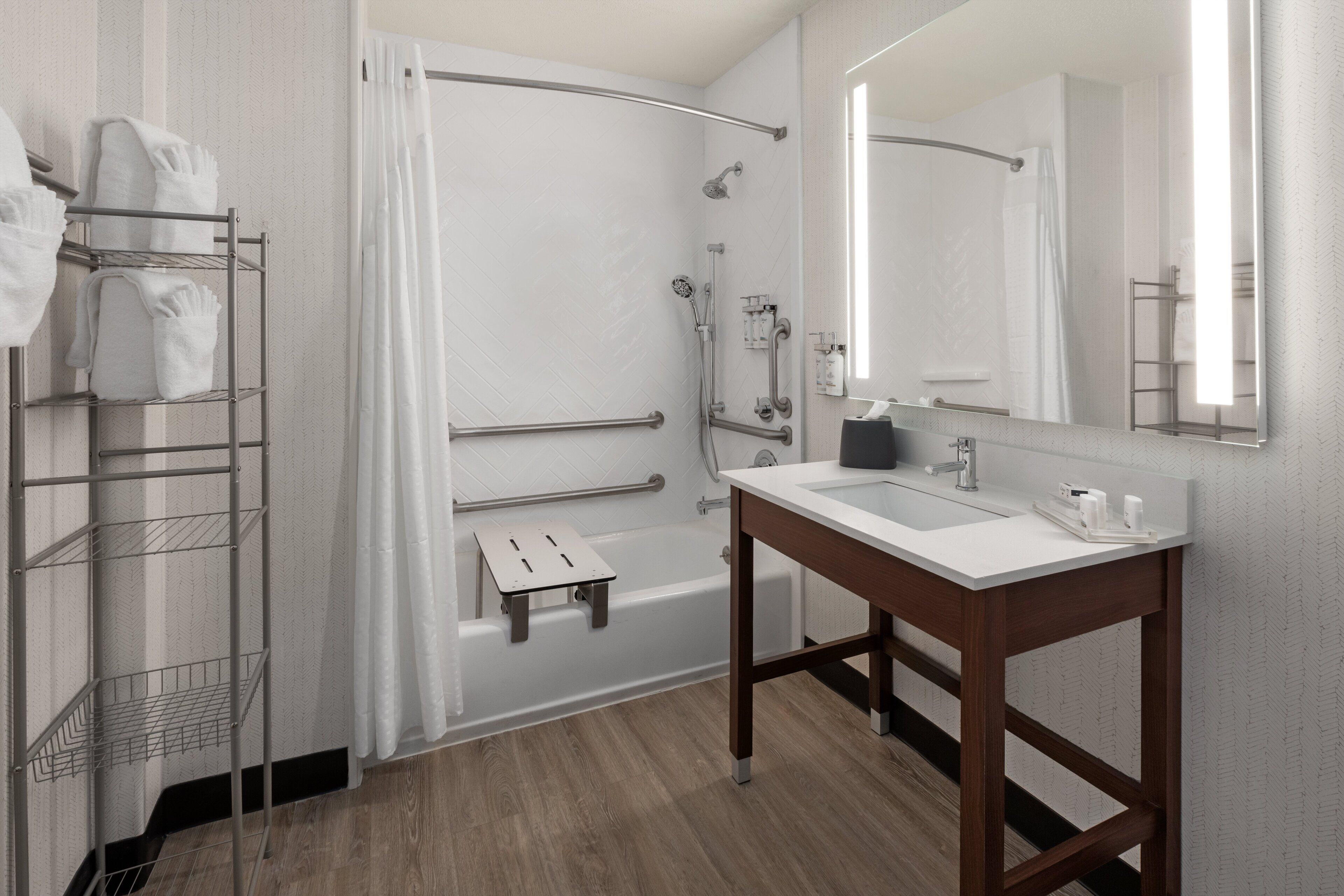 Een moderne badkamer met een douche, wastafel, spiegel en handdoekrek.
