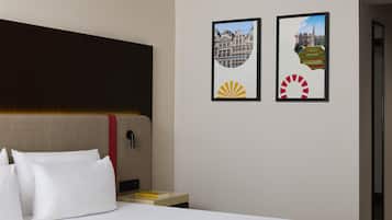 Une chambre d’hôtel avec un lit, une table de chevet et deux tableaux encadrés au mur.