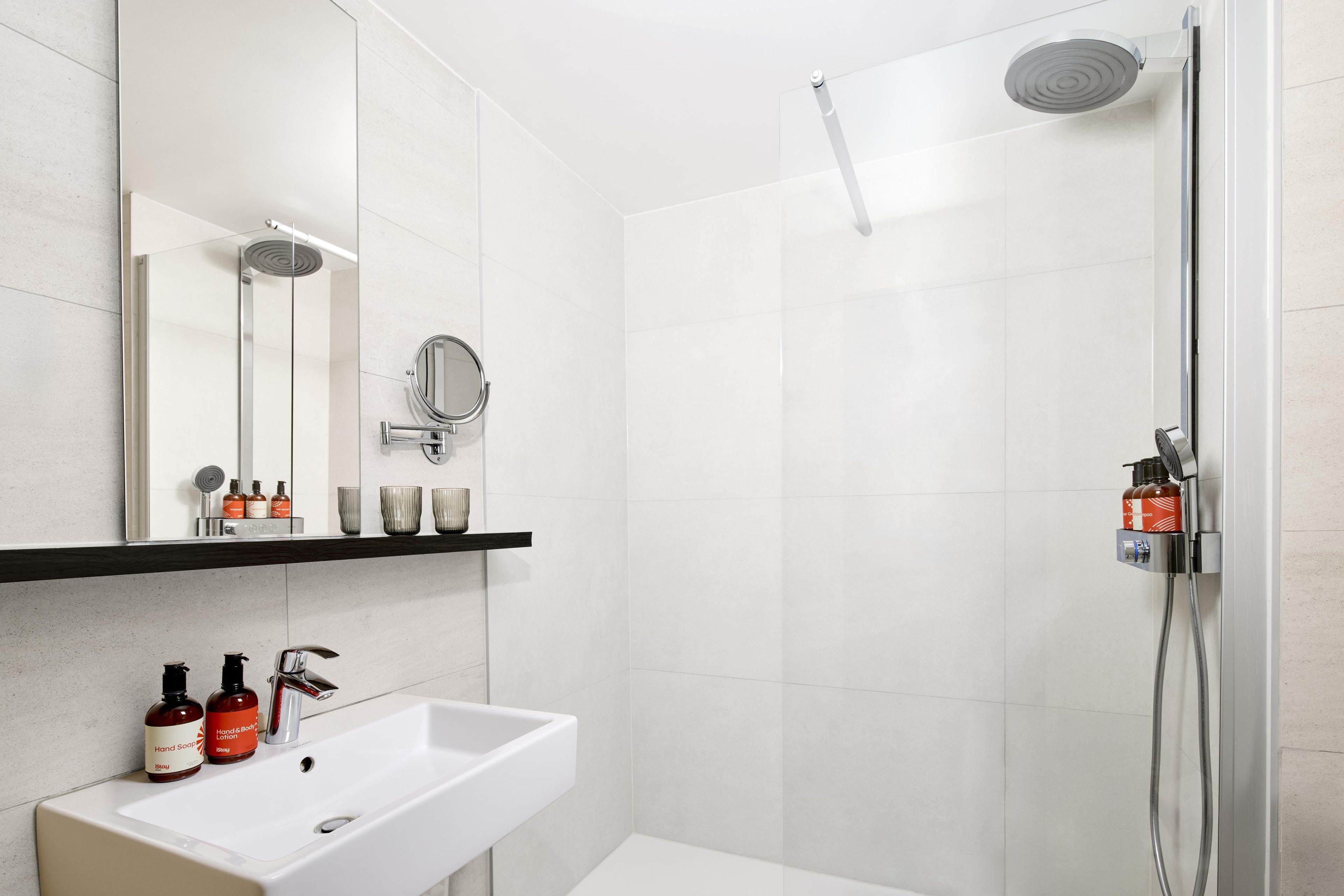 Un baño moderno con un lavamanos blanco, un espejo y una ducha.