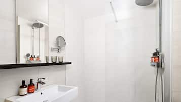 Un baño moderno con un lavamanos blanco, un espejo y una ducha.