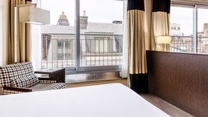 Una habitación de hotel con un ventanal grande, una cama, una silla y una mesa.