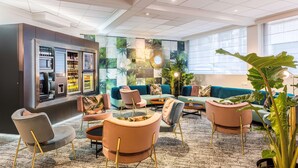 Un espacio lounge moderno con sofás, sillones y una zona de bar con refrigerador y estanterías.