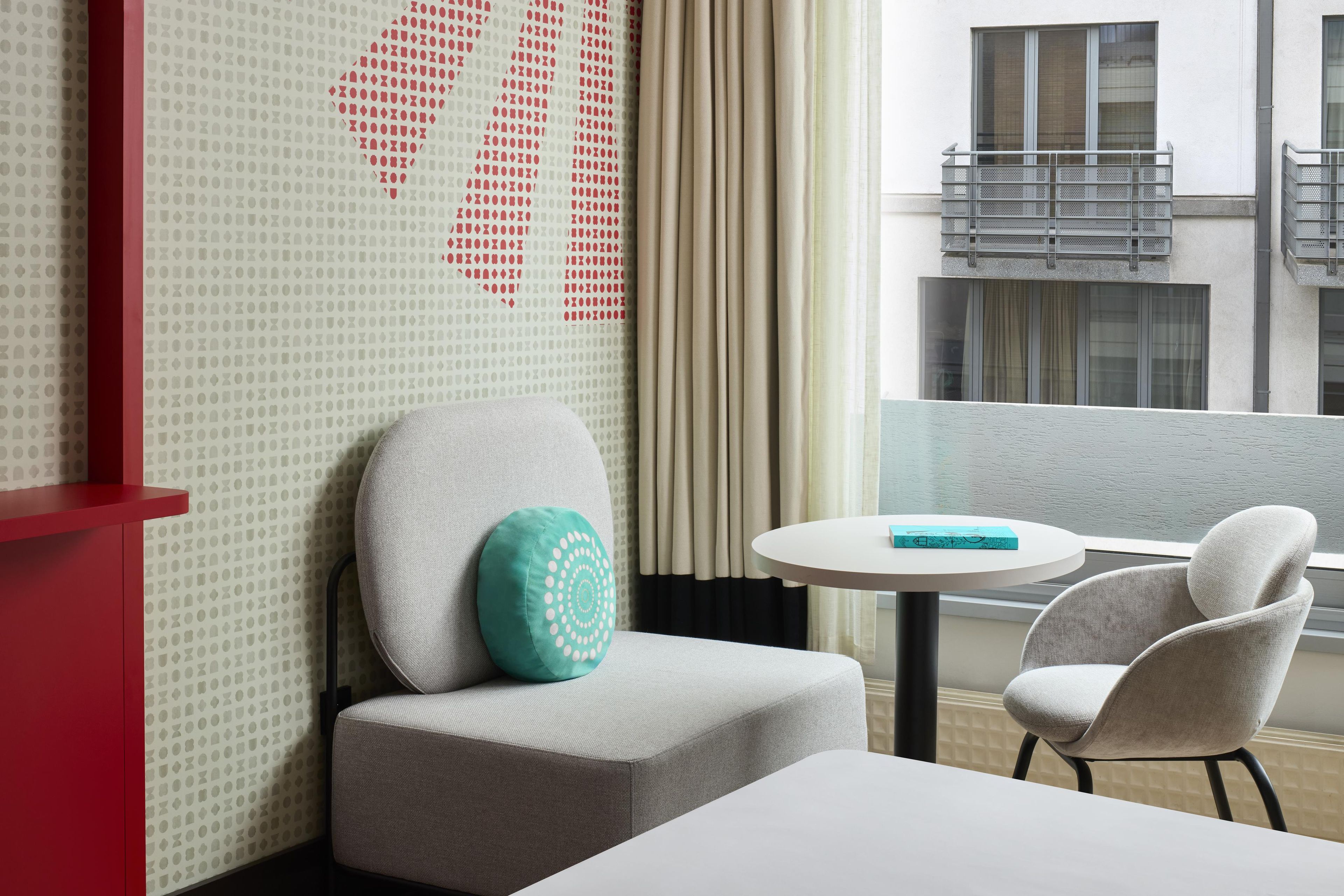 Habitación de hotel con sofá, una mesita y vistas al exterior del edificio.