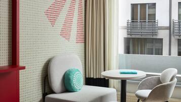 Habitación de hotel con sofá, una mesita y vistas al exterior del edificio.