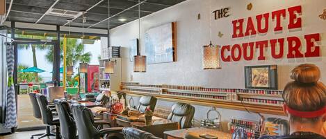 Ein Salon mit Empfangstresen, Ledersesseln und einer Wand, auf der das Schild 'The Haute Couture' zu sehen ist.