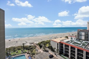 Un hotel con piscina en la azotea, vistas a la playa y aparcamiento.