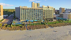 A large hotel with multiple floors, a pool area, and a beach in the foreground. - Sand Dunes Resort and Suites (Myrtle Beach)