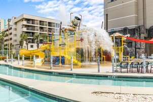 A water park with a yellow slide, water jets, and a pool.