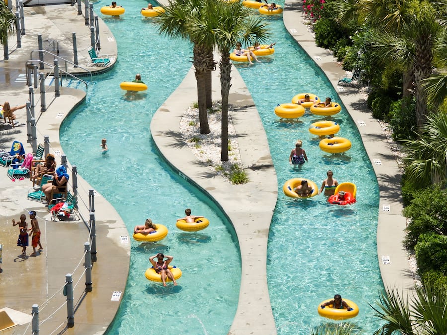 Parque aquático com várias piscinas e pessoas usando boias.