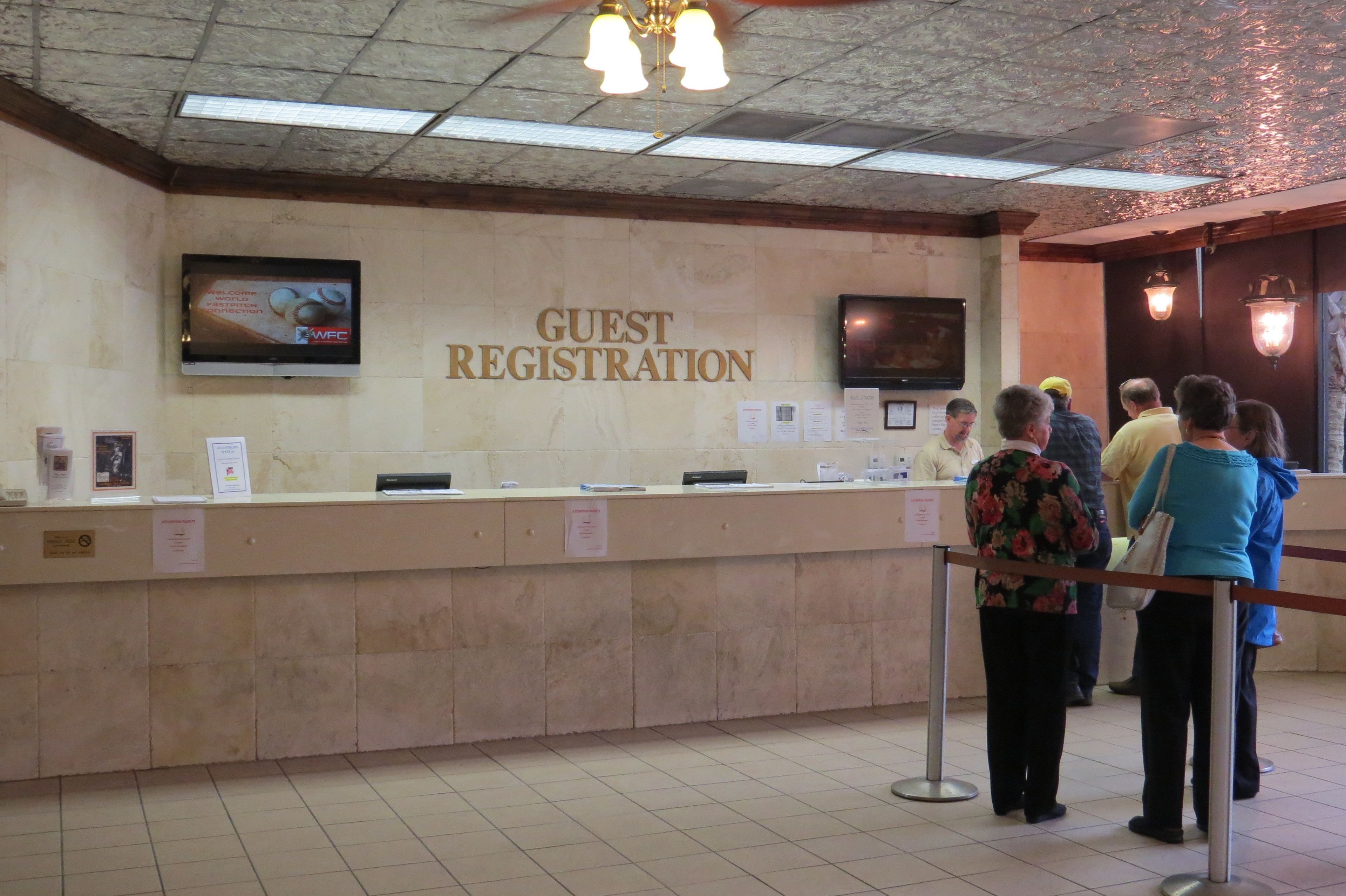 A guest registration area with a reception desk, a television screen, and a wall-mounted sign.