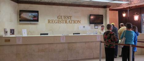 A guest registration area with a reception desk, a television screen, and a wall-mounted sign.