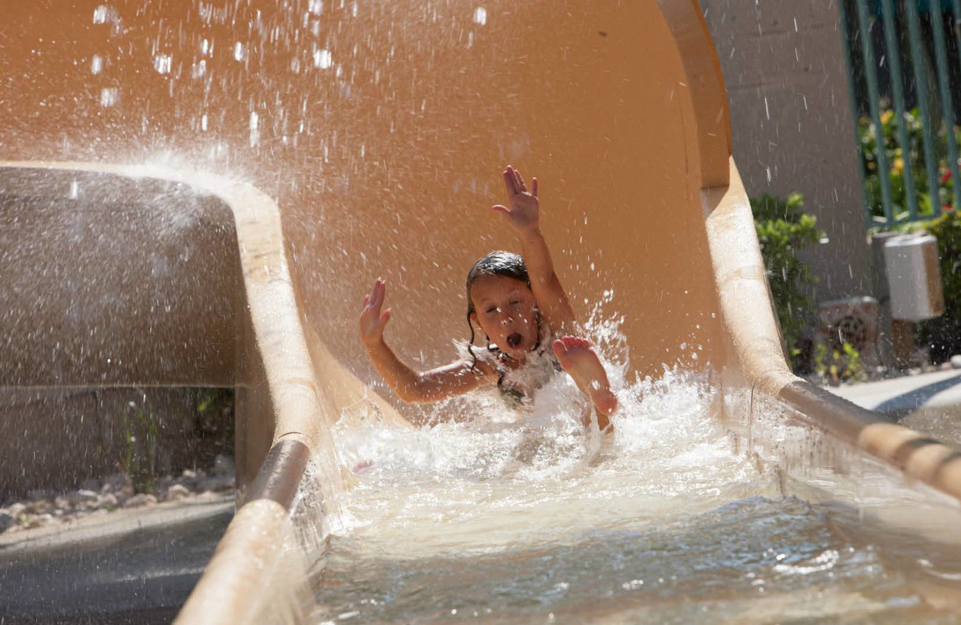 A child sliding down a water slide with water splashing around.