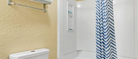 A bathroom with a white bathtub, a shower curtain with a blue and white zigzag pattern, and a towel rack with a white towel.