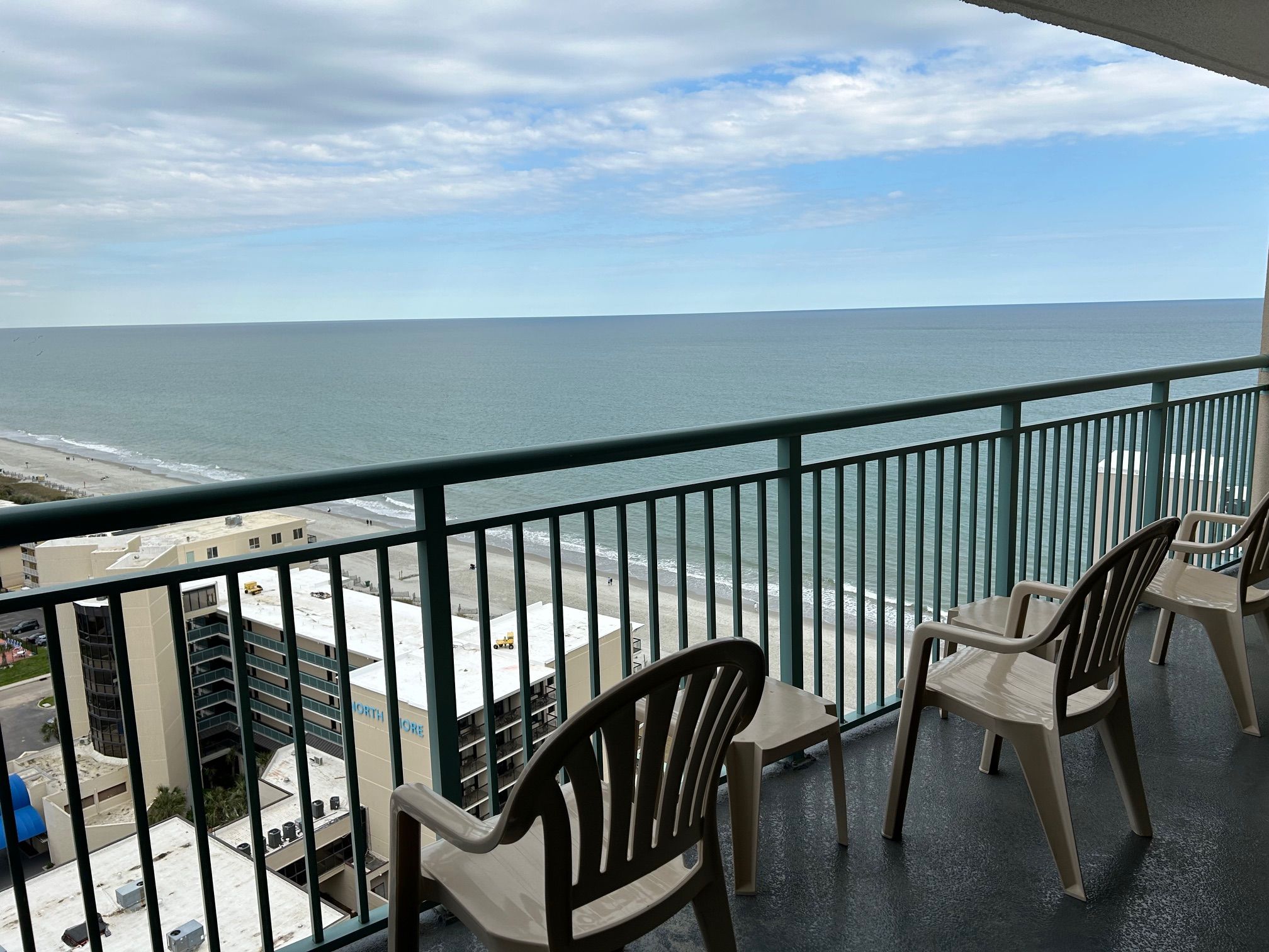 A balcony with a view of the ocean, featuring two chairs and a table.