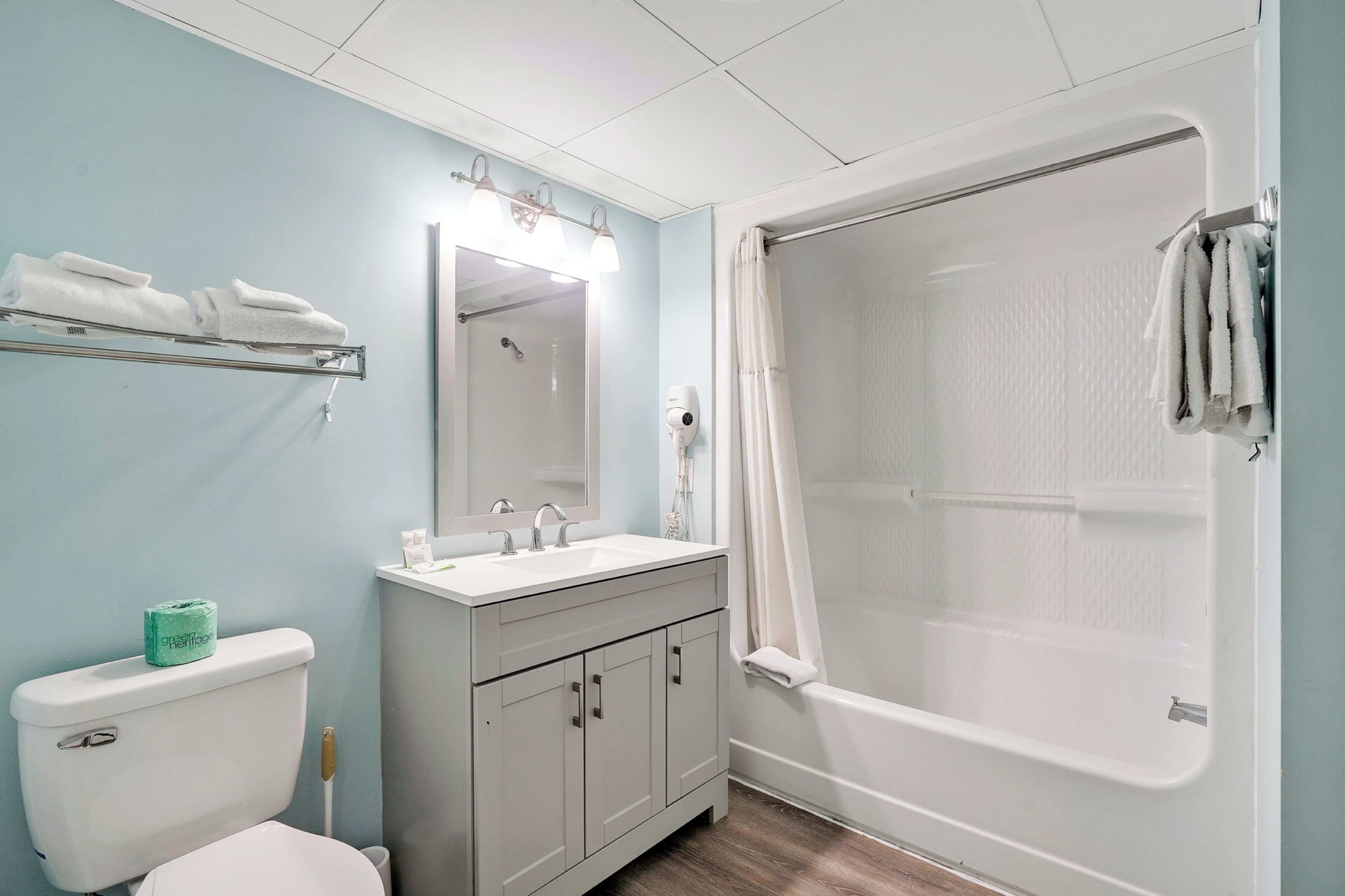 A bathroom with a toilet, sink, vanity, and a walk-in shower.
