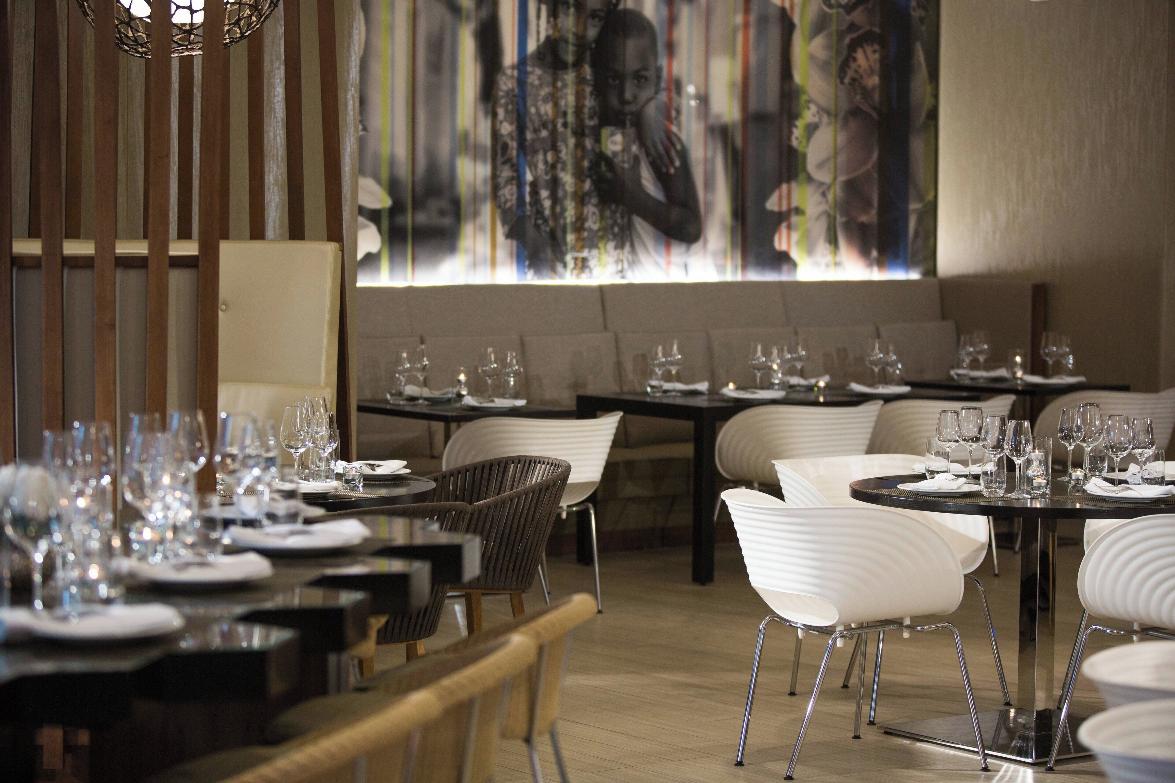 Un restaurante con varias mesas dispuestas para comer, con sillas modernas y una decoración interior contemporánea.