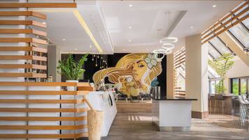 Un vestíbulo de hotel moderno con una recepción, un mural y una zona de bar.