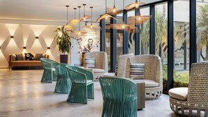 A modern lounge area with wicker furniture, pendant lighting, and a large window offering a view of the outdoors. - Renaissance Santo Domingo Jaragua Hotel & Casino (Santo Domingo)