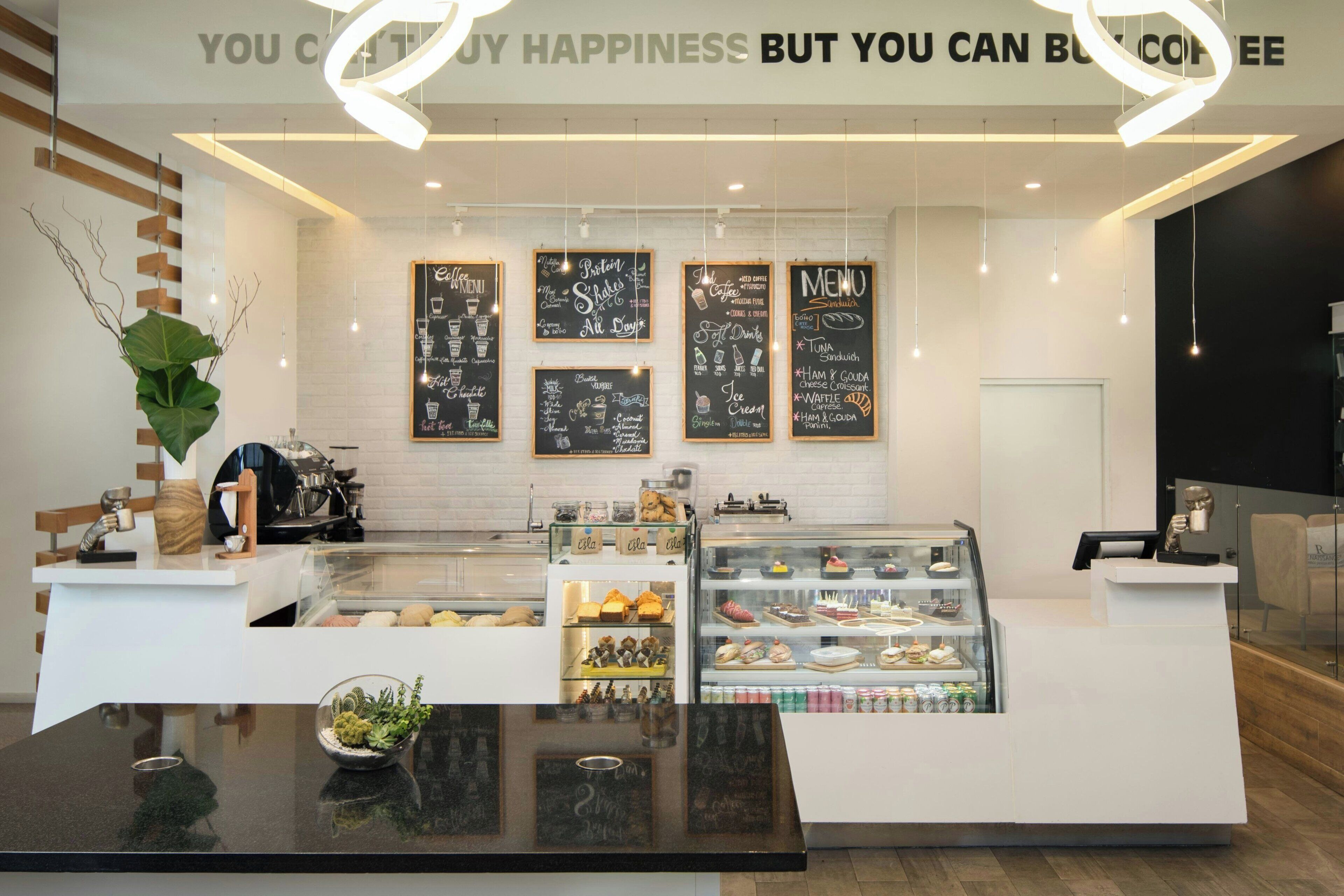 Ein modernes Café-Interieur mit einer Theke, Speisekartenauslagen und einer Vitrine voller Gebäck.