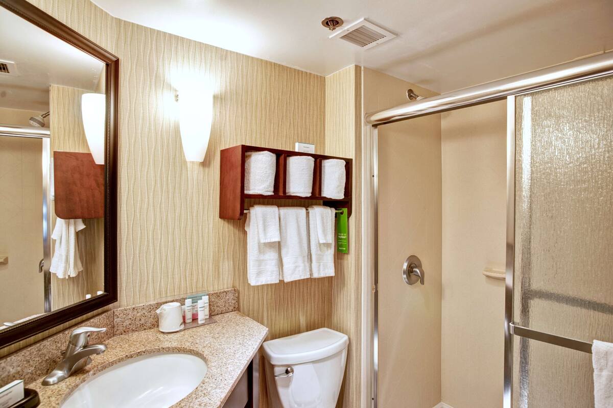 A bathroom with two sinks, a toilet, a shower, and a mirror.
