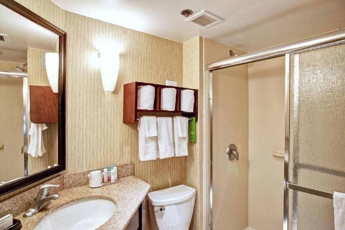 A bathroom with two sinks, a toilet, a shower, a mirror, and a towel rack.