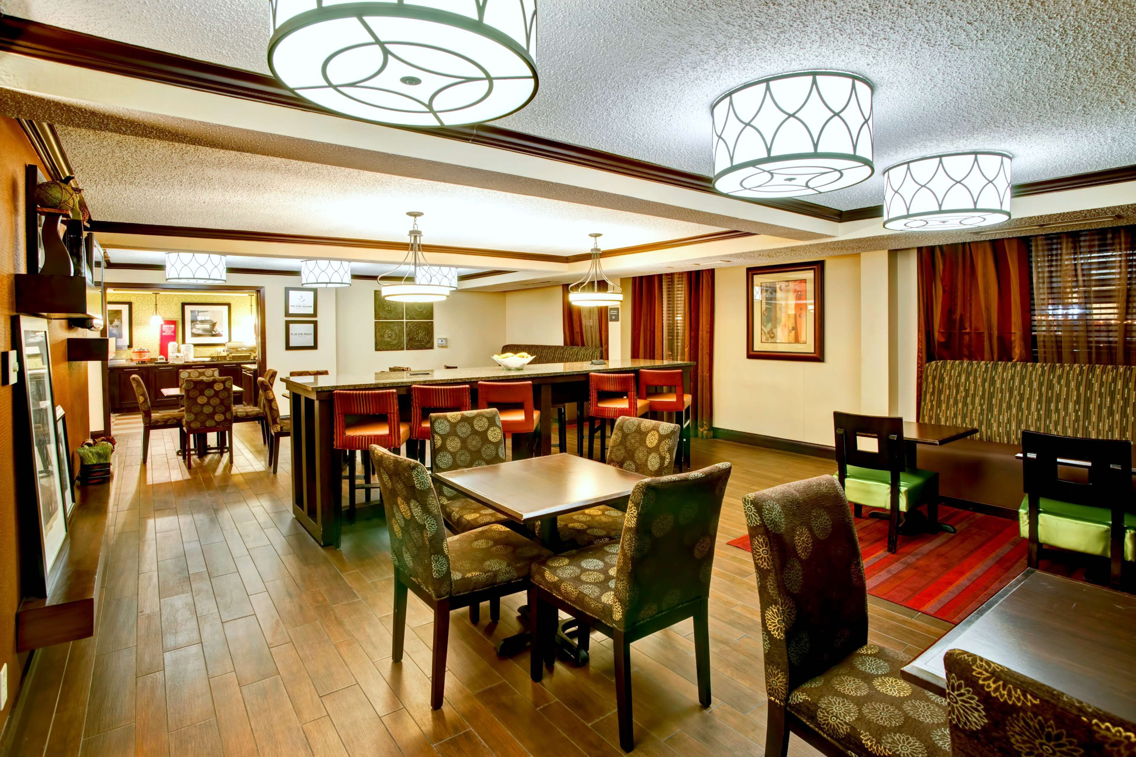 Un comedor de hotel con varias mesas y sillas, un bar y una cocina al fondo.