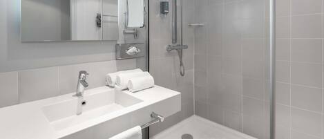 A modern bathroom with a white sink, mirror, and a walk-in shower.
