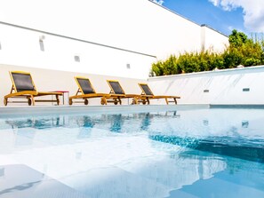 Una piscina al aire libre de temporada, sombrillas