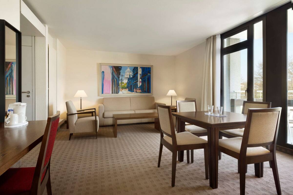 Une chambre d’hôtel avec un coin repas, un canapé et un tableau au mur.
