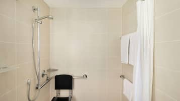 A shower area with a grab bar, a towel rack, and a showerhead.