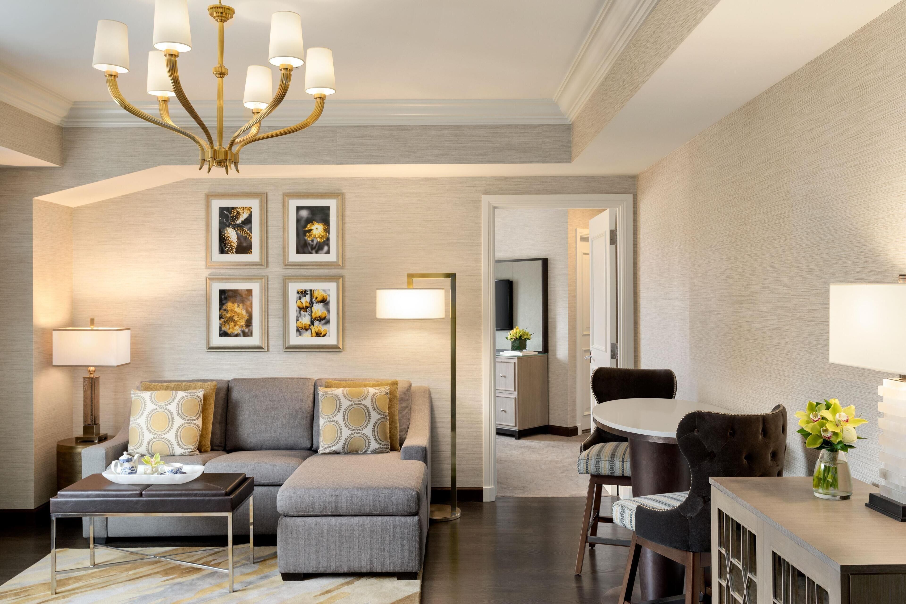 Una sala de estar moderna con un sofá, una mesa de centro, un comedor con mesa y sillas, y un candelabro.