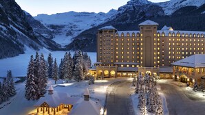Ein großes Hotel mit mehreren Gebäuden, umgeben von schneebedeckten Bergen und Bäumen.