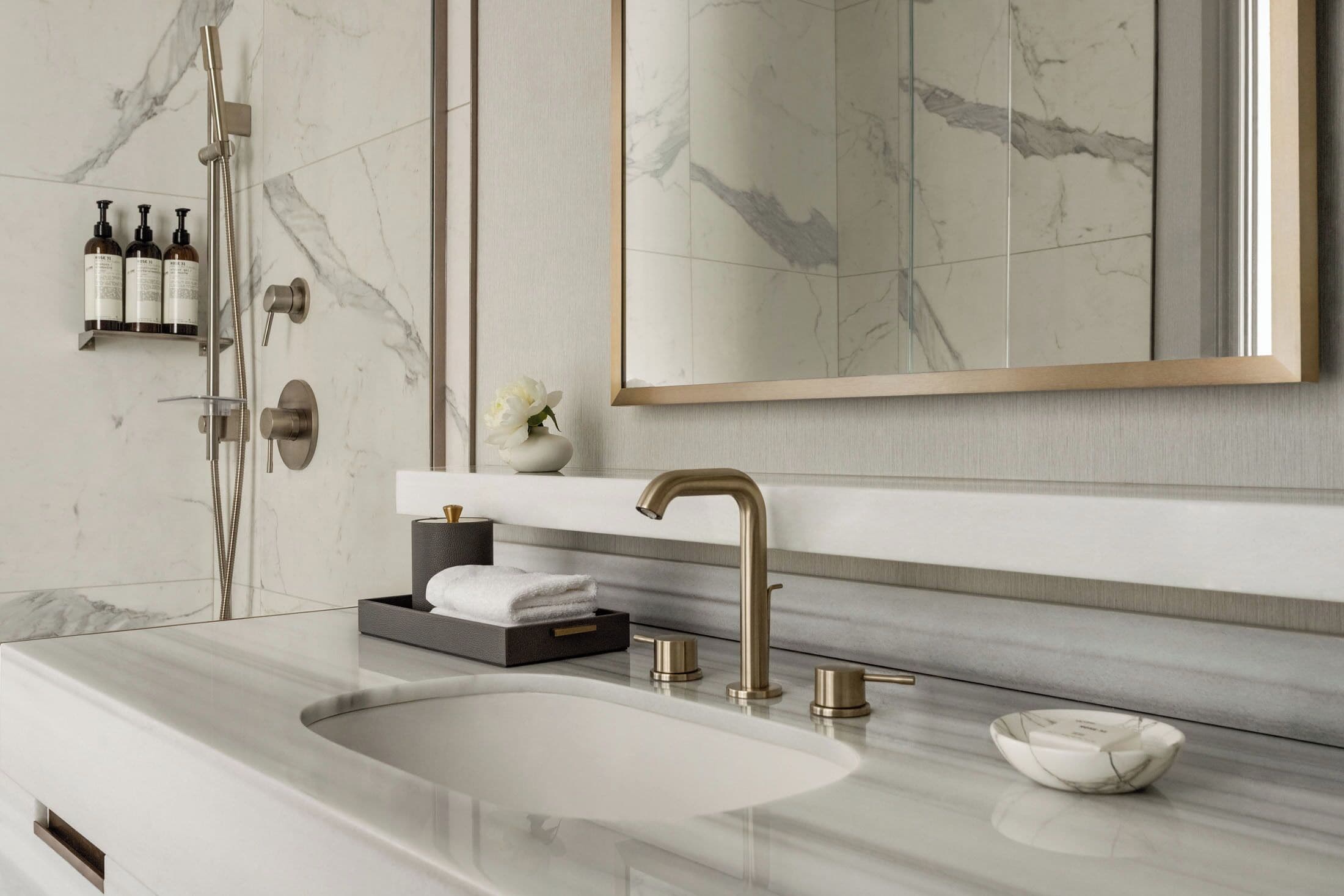 A modern bathroom with a marble sink, a large mirror, and a shower with a handheld showerhead.