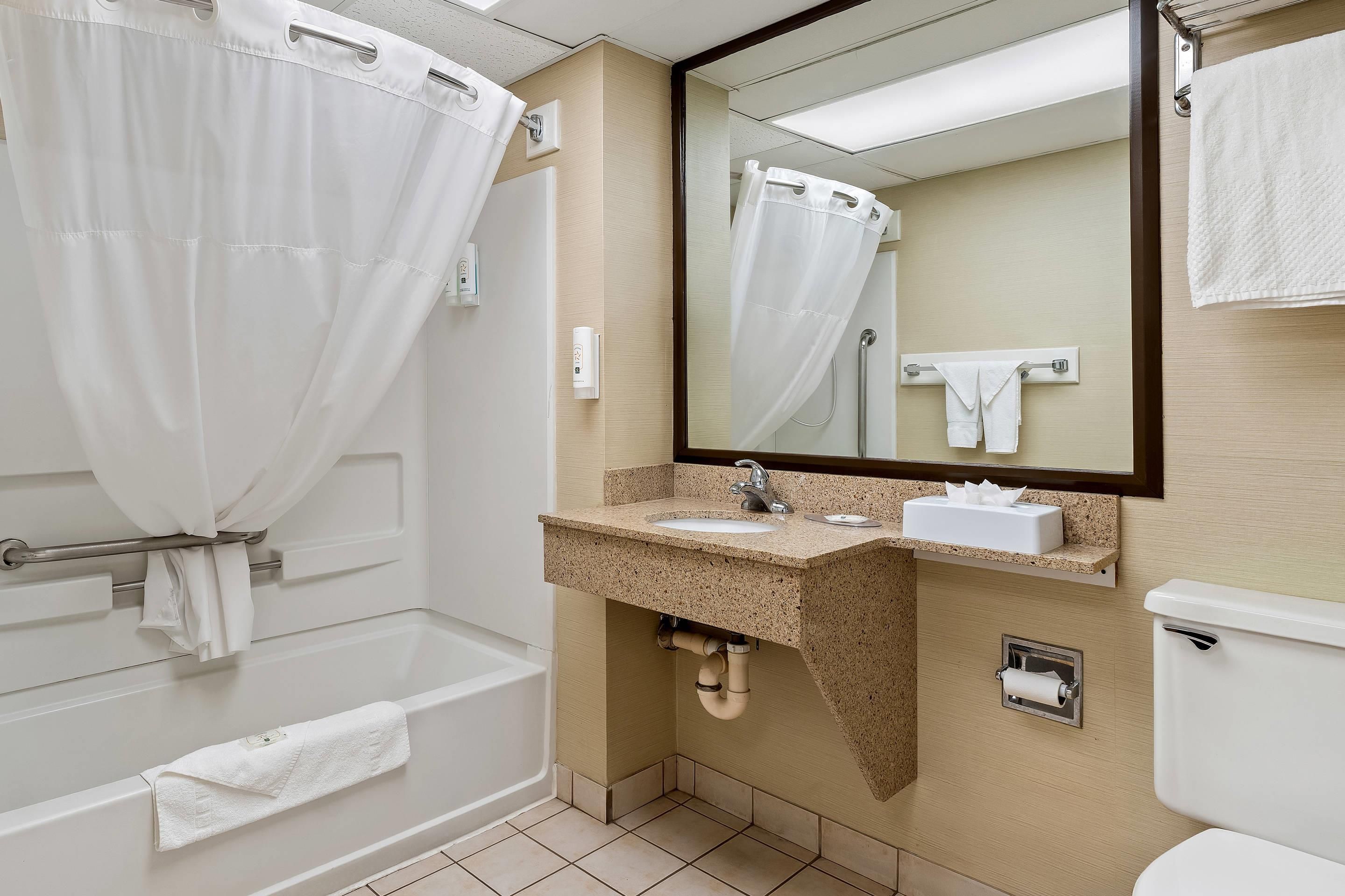 A bathroom with a bathtub, a sink, a toilet, and a mirror.