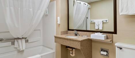 A bathroom with a bathtub, a sink, a toilet, and a mirror.