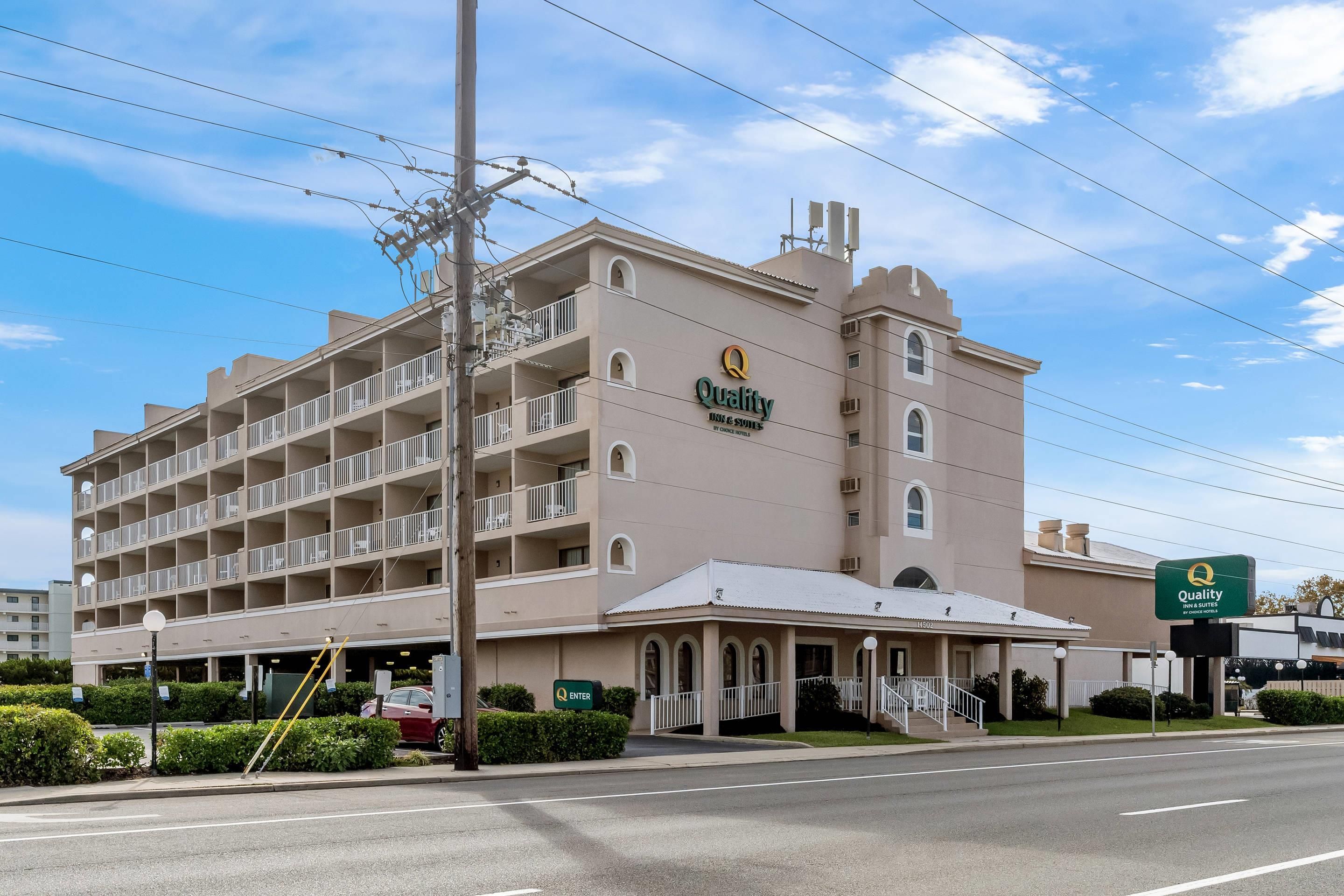 A multi-story hotel with a beige facade, a prominent 'Quality Inn & Suites' sign, and a green 'Enter' sign at the entrance.