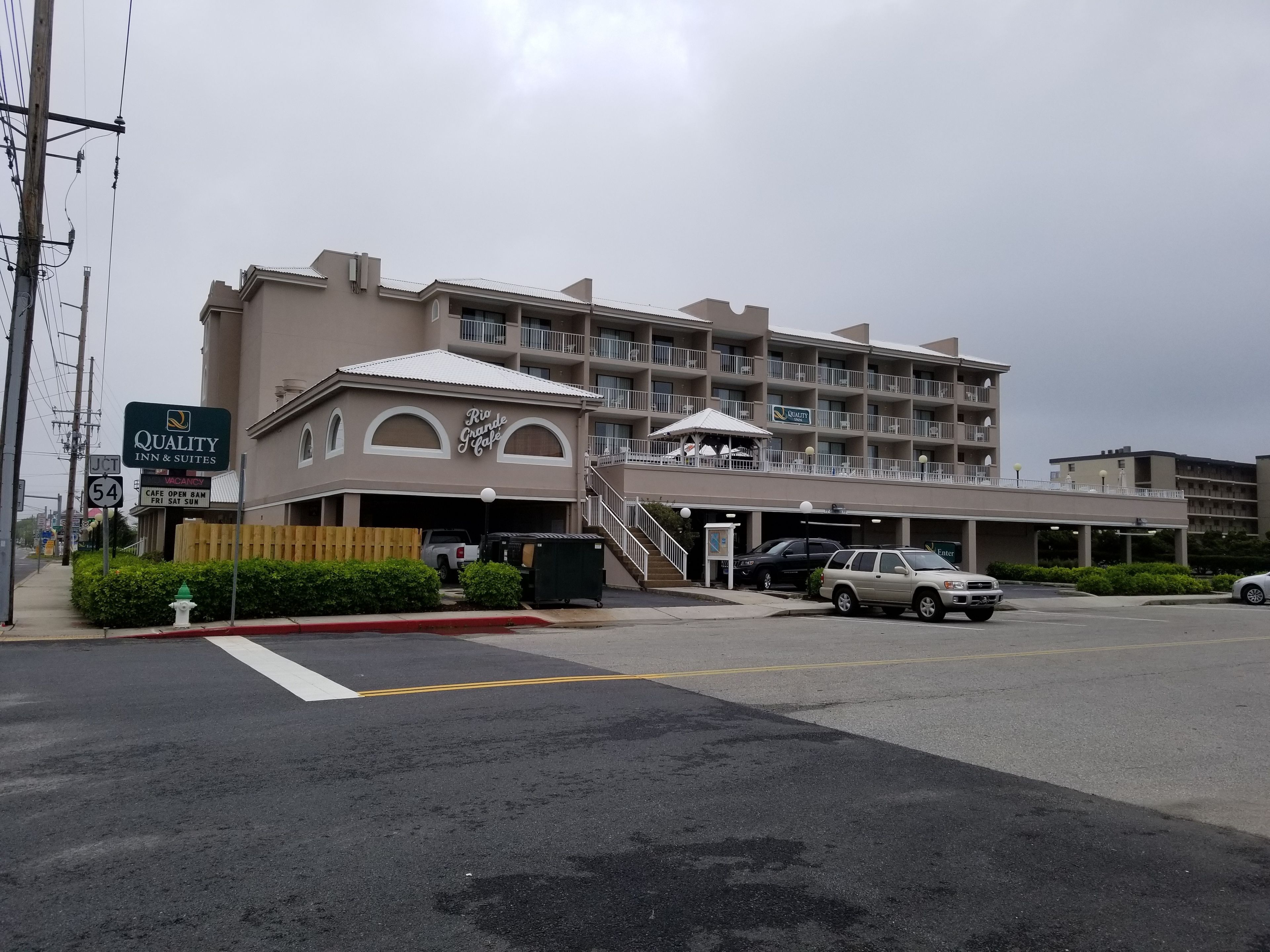 A hotel with a two-story structure, a covered entrance, and a parking area with several cars.