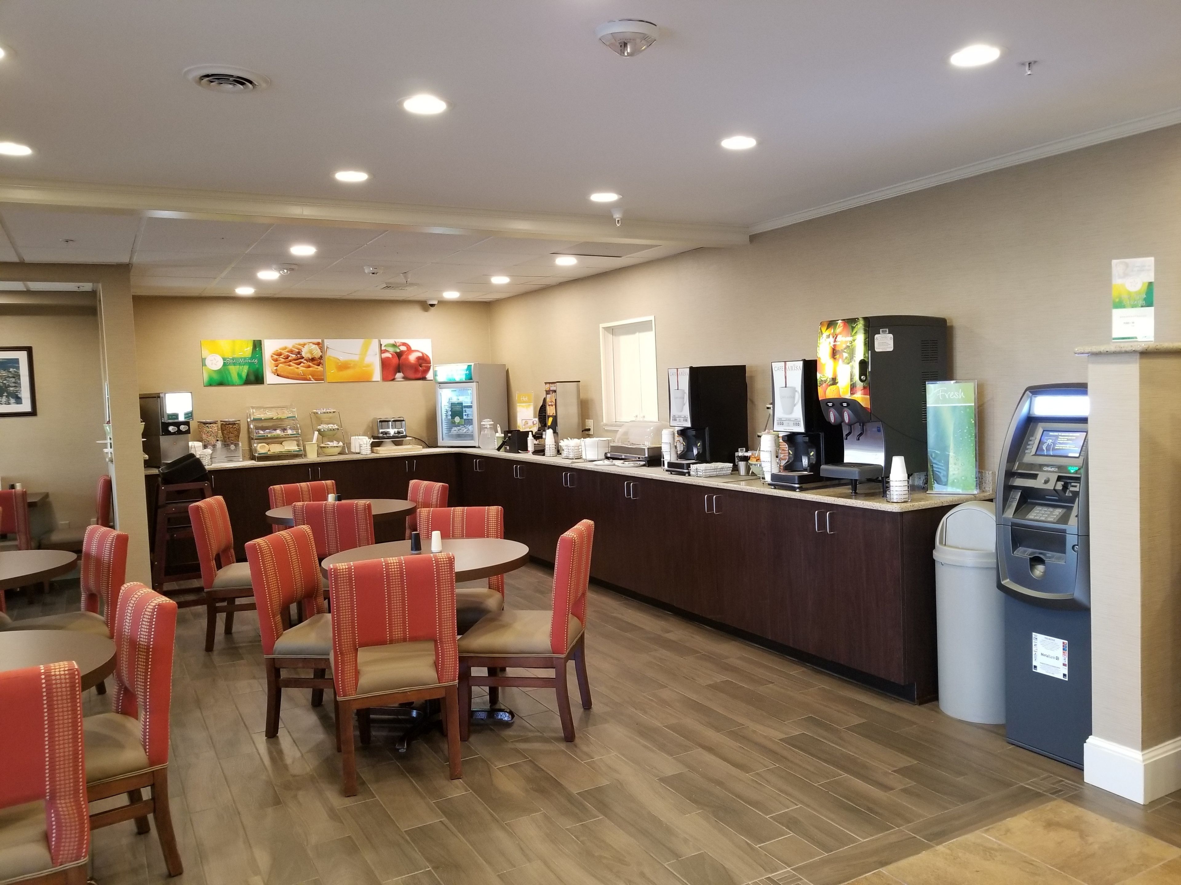 A restaurant with a counter, seating area, and a trash bin.