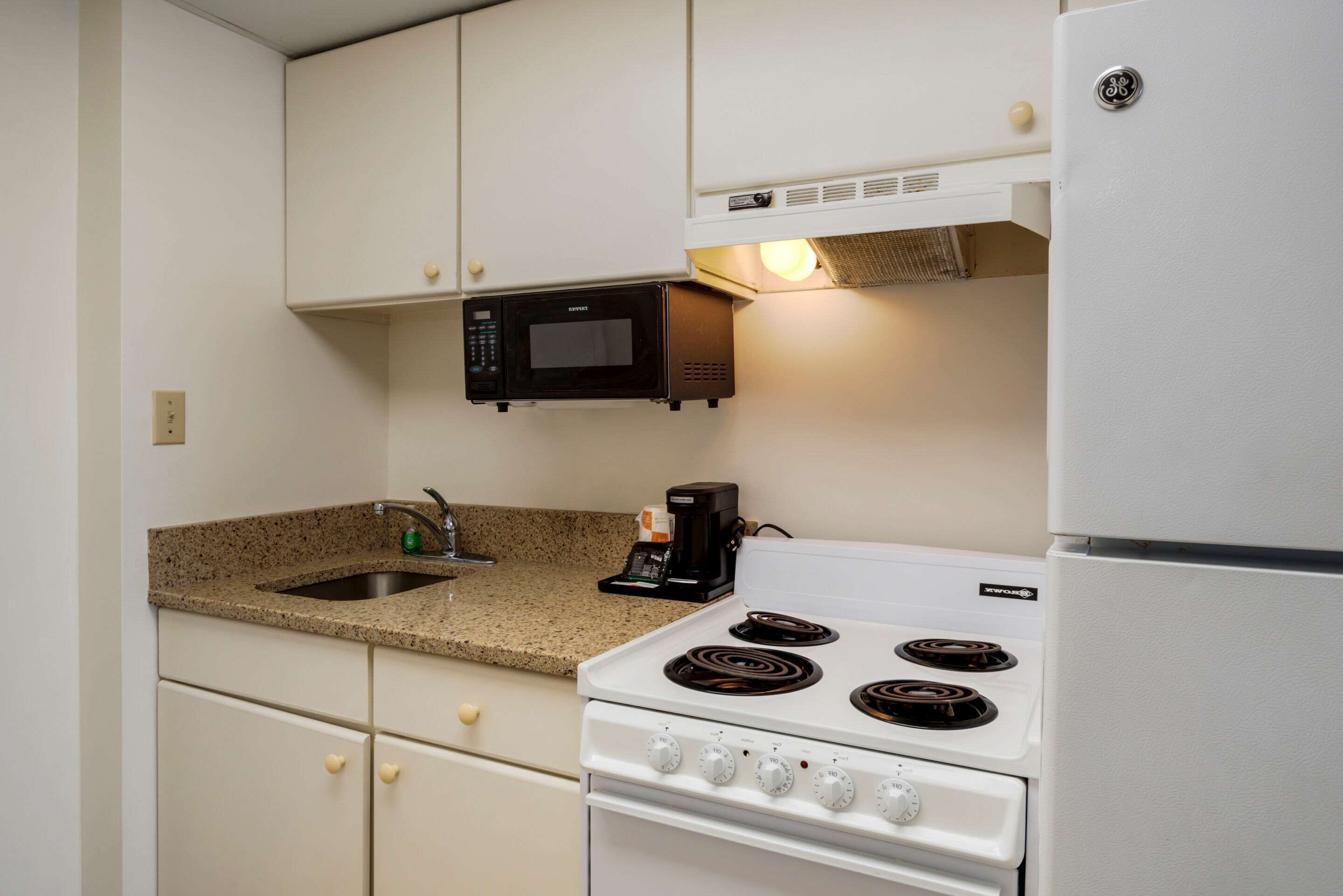 A compact kitchen with a white stove, a microwave, and a coffee maker.