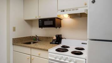 A compact kitchen with a white stove, a microwave, and a coffee maker.